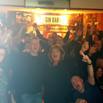 Shot from the band's perspective on stage, the crowd at the Jolly Nailor, Atherton, smiling, cheering and waving their arms.