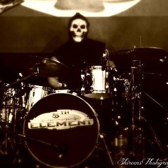 Aaron playing drums, wearing a grim reaper mask. Black and white.