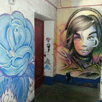 A mural graffiti design of a girl listening to music on headphones and a blue rose.