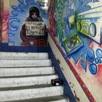 A mural graffiti design of a beggar girl holding a sign that says 'Keep your coins, I want change.'