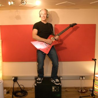 Neil standing on top of his amp at the studio, colour.