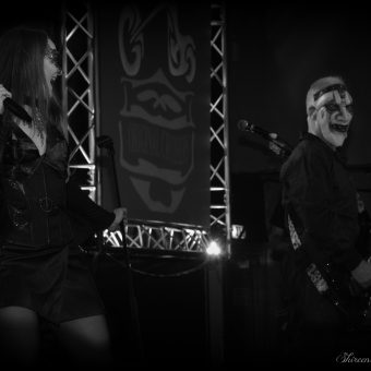 Ann and Neil performing on stage. Neil is wearing a scary Halloween mask.