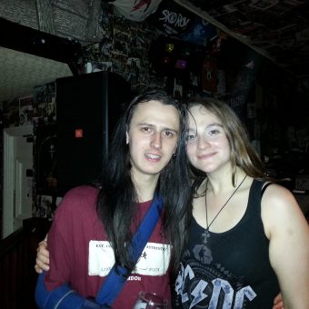 A man with long black hair (Jakey) and Ann posing for the camera.
