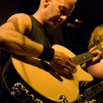 Neil playing acoustic guitar.