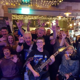 The crowd at Remedy Bar and Brewhouse, Stockport, cheering and waving their arms.