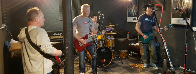 Pete, Neil, Aaron and Alan playing songs in a rehearsal room.